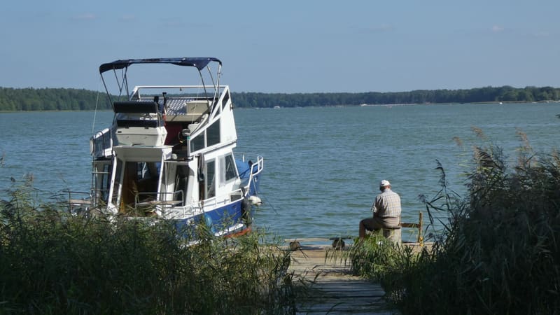 Tom Cat moored beside a wooden jetty, lake in the background